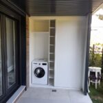 Armarios para Lavadora Exterior: La Solución Definitiva para tu Zona de Colada a Medida con Parquets Prieto Armario abierto mostrando la lavadora en su hueco.