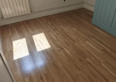 Tarima maciza de roble acuchillada y barnizada en poliuretano satinado con rodapié blanco en Madrid