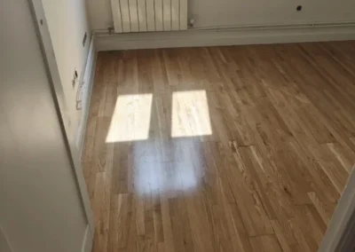 Tarima maciza de roble acuchillada y barnizada en poliuretano satinado con rodapié blanco en Madrid